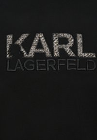 Text s nápisom "KARL LAGERFELD" s tkanou textúrou v písmenách "KARL" na čiernom pozadí.