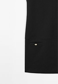 Zwarte roksectie met een klein klepzakje met een enkele zilveren knoopdetail, tegen een witte achtergrond.
