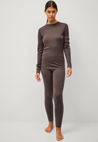 Bruine lange mouw top met een ronde halslijn, gecombineerd met bijpassende aansluitende leggings. Zacht materiaal met minimale naden en een eenvoudig ontwerp.