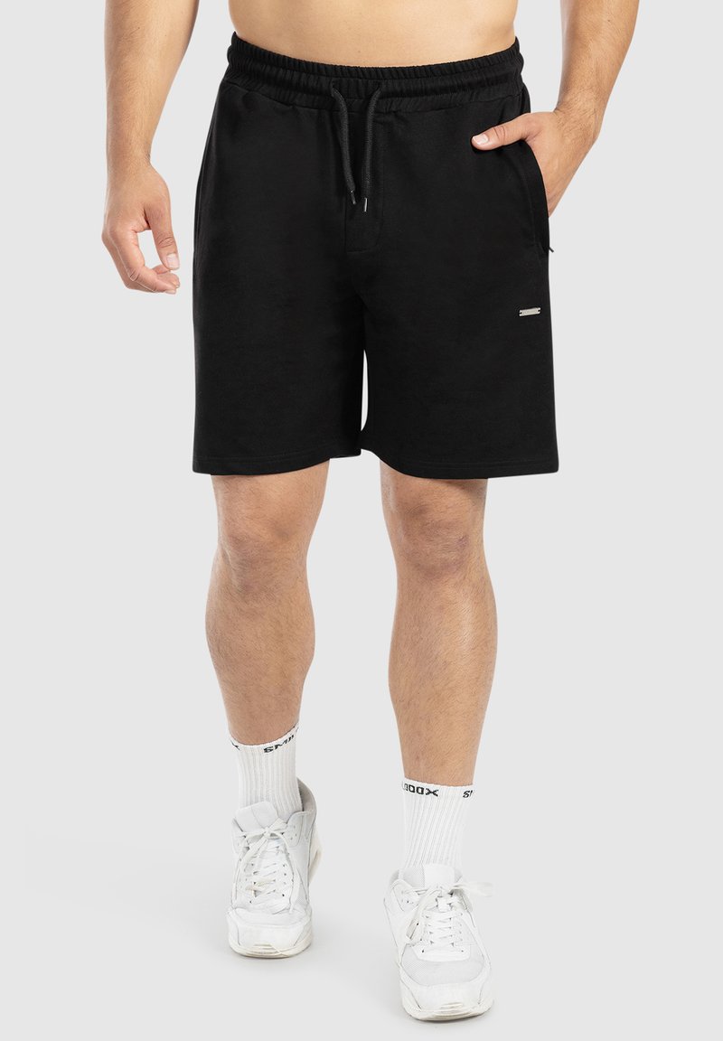 Shorts de algodón negros con cintura ajustable mediante cordón, bolsillos laterales, textura suave y un pequeño detalle en plata en el frente.