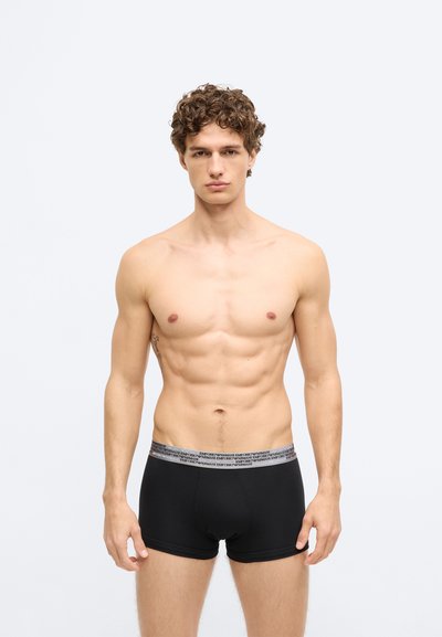 Fekete pamut boxermore, strukturált elasztikus derékpánttal, melyen egy logó látható. Egyszerű, testhez simuló kialakítás minimális díszítéssel.