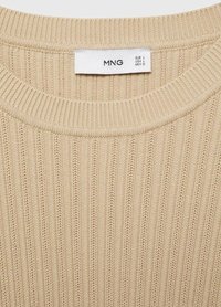 Beige neulotussa on ribbikuvio, pyöreä pääntie ja etiketti, jossa on koko tiedot. Pehmeä kangas, jossa on pystysuoria viivoja ja hienoinen kiilto.