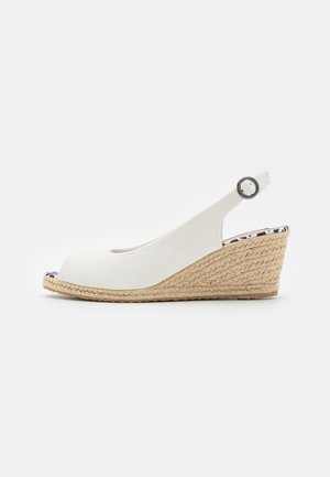 Sandalia cuña con tiras traseras de lona blanca, tacón de yute trenzado y cierre de hebilla plateada, con diseño de punta abierta y plantilla estampada.