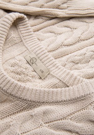 Maglione beige a maglia grossa con scollatura a costine e texture. Etichetta visibile che indica la taglia e il marchio attaccata all'orlo inferiore.