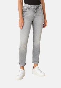 Jeans in denim grigio chiaro con una vestibilità slim, orli arrotolati e design a cinque tasche, abbinati a sneaker platform bianche.