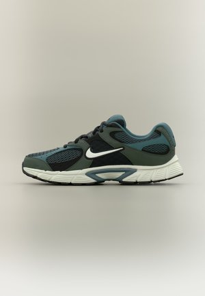 Ciemnozielony i czarny but do biegania Nike z białą podeszwą i białym logo Swoosh, widok z boku na neutralnym tle.