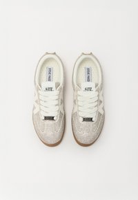 Hvite sneakers med et mønstret, sølvstuddet overdel, teksturerte gummisåler, runde lisser og merkevare på tungen.
