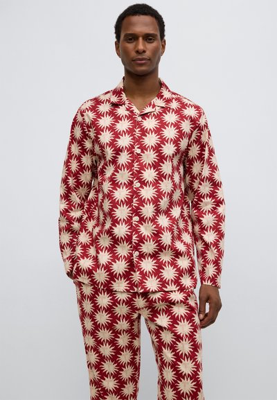 Set de pijamale roșu și crem cu modele în formă de explozie stea, cămașă cu nasturi și pantaloni lungi din material moale.
