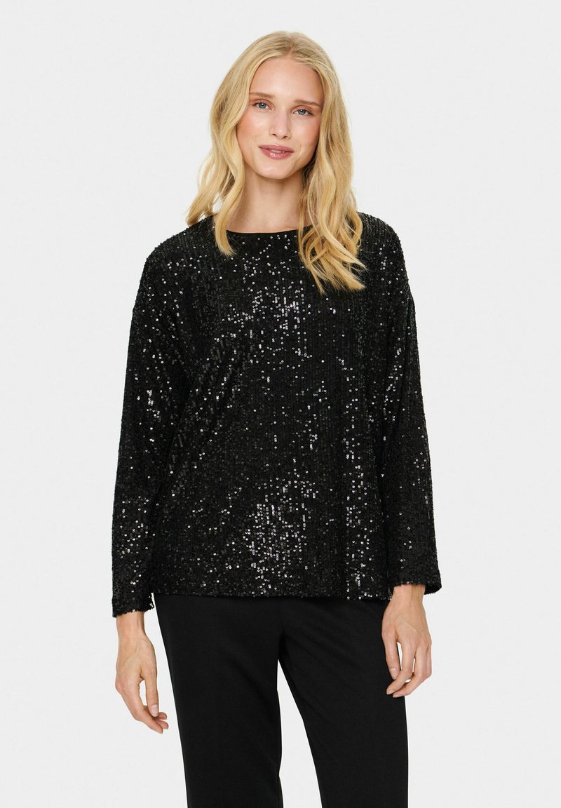 Top nero con paillettes, maniche lunghe e scollatura rotonda, caratterizzato da una vestibilità ampia e una superficie texturizzata e luccicante. Abbinato a pantaloni neri.
