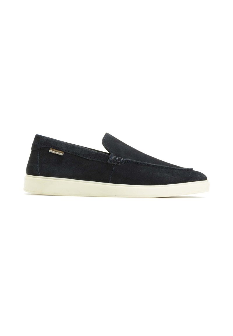 Schwarze Wildleder-Slipper mit minimalistischem Design, weißer Gummisohle und Akzentnähten. Mit einem kleinen Markenschild an der Seite.