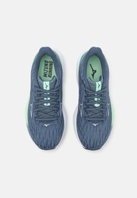 Hardloopschoenen in marineblauw en lichtgroen. Voorzien van een gestructureerde bovenkant, witte tussenzool en gestreepte veters. Merklogo op de binnenzool.
