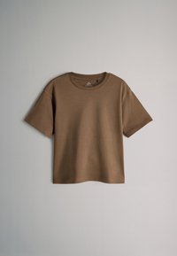 T-shirt marron à manches courtes avec col rond, présenté à plat sur un fond gris.
