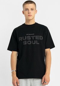 Czarna bawełniana koszulka z krótkimi rękawami i okrągłym dekoltem. Na piersi widnieje wyraźny szary napis "UNFINISHED RUSTED SOUL".