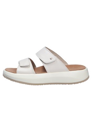 Chanclas de color beige claro con dos correas de Velcro ajustables, parte superior de cuero suave, plantilla acolchada y suela exterior de goma blanca gruesa.