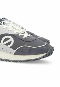 Zapatillas grises con acentos blancos, fabricadas con materiales de ante y tela, con forma de punta redonda y suela de goma texturizada para un mejor agarre.