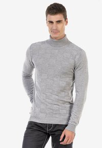 Grijze gebreide coltrui met een getextureerd, gewatteerd patroon, lange mouwen en een geribde zoom. Gekenmerkt met donkere jeans.