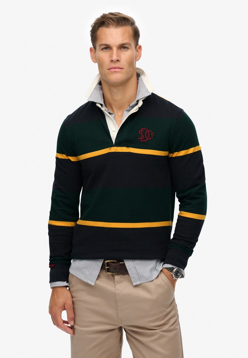 Langsleeve polo shirt in groen, marineblauw en gele strepen, met een kraagontwerp en geborduurd logo op de borst. Subtiele geruite onderkraag.