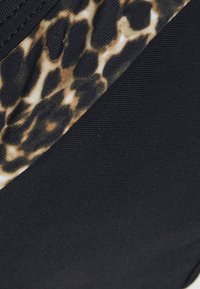 Juodas maudymosi šortai su leopardų raštu viršuje. Medžiaga atrodo elastinga, lygus paviršius ir gerai priglunda.