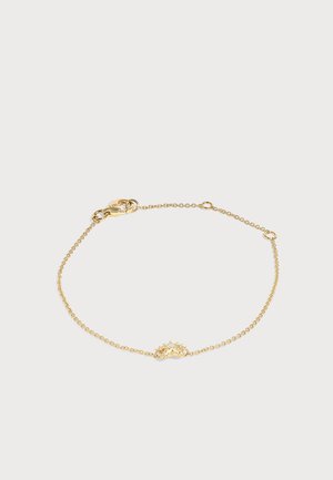 Bracelet délicat en chaîne dorée avec un petit pendentif en forme de soleil et une fermeture à mousqueton sur un fond uni.