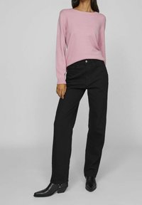 Ljust rosa stickad tröja med långa ärmar, kombinerad med svarta raka jeans. Svarta spetsiga ankelboots med låg klack.