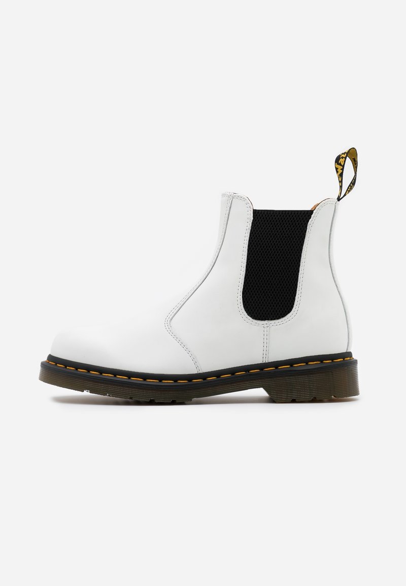 Botte Chelsea blanche avec panneau latéral élastique noir, surpiqûres jaunes sur la semelle noire et languette de tirage de marque au talon.