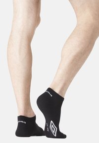 Chaussettes noires jusqu'à la cheville avec logo blanc et motif en losange au talon, en tissu avec une texture lisse. Longueur mi-mollet.