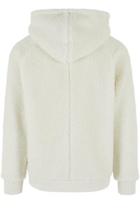 Cream-colored hoodie made of fuzzy, plush fabric. Features a large hood, ribbed cuffs, and a straight hem. Seam detailing on the back.
