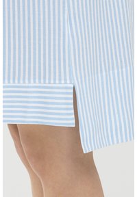 Tissu rayé vertical bleu et blanc avec une fente à l'ourlet, présentant une texture lisse et une finition ajustée à la base.