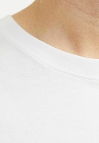 Hvid bomulds t-shirt med rund halsudskæring og en glat tekstur. Stoffet virker let med en let glans og præcise sømme.
