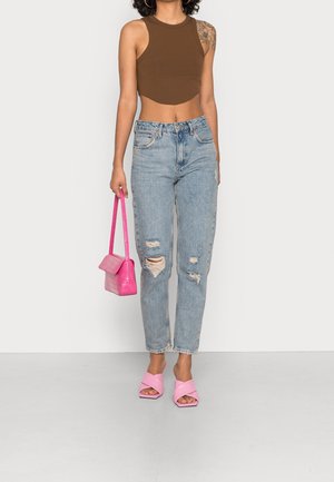 Brun randig crop top, ljusblå slitna jeans, rosa axelväska med texturmönster och rosa klacksandaler med blockklack.