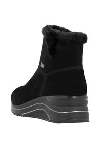 Bottines noires avec une douce bordure en fausse fourrure, tige en daim, bout arrondi et un épais talon compensé avec une semelle en caoutchouc texturé.