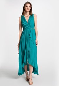Robe maxi plissée bleu sarcelle avec un décolleté en V, un ourlet asymétrique et des accents volantés. Deux ornements dorés à la taille.