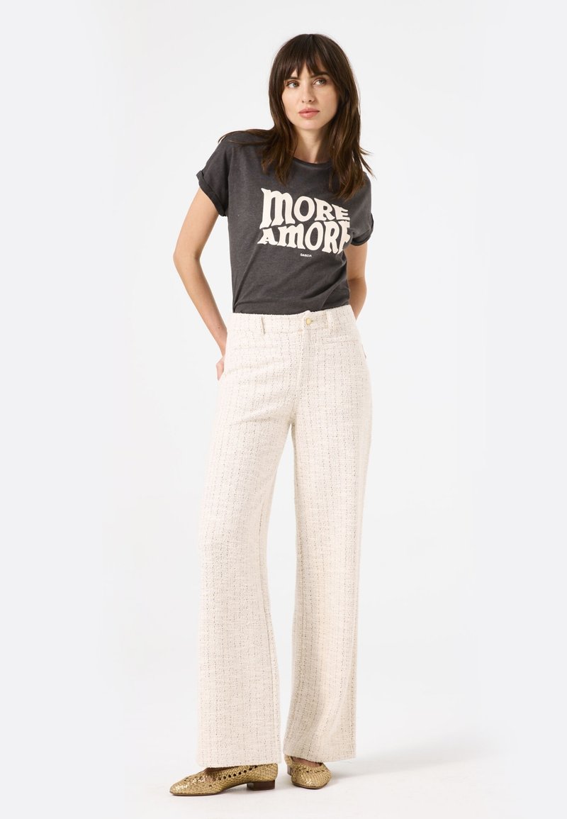 Grijze t-shirt met de opdruk "MORE AMORE", gecombineerd met hoge taille, wijde, textuur witte broek en gouden flats. Eenvoudig, modern ontwerp.