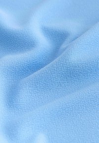Tissu bleu clair doux avec une texture fine tricotée et des plis délicats créant des ombres subtiles.