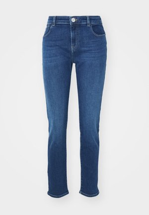 Jeans in denim blu scuro con un design aderente, vita media, cinque tasche e un orlo leggermente sfilacciato alle caviglie.