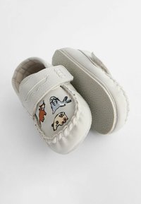 White baby moccasins with a textured sole, featuring embroidered animal designs in brown, gray, and blue on the front and a Velcro strap.