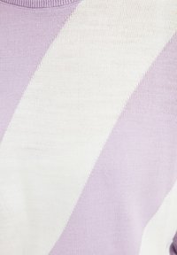 Detailní pohled na pletenou tkaninu se šikmými levandulovými a bílými pruhy a vroubkovaným levandulovým výstřihem.