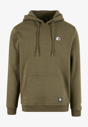 Alyvuogių žalios spalvos džemperis su kengūros tipo kišene, reguliuojamu raišteliu prie gobtuvo ir mažu baltu logotipo lipduku ant krūtinės. Minkšta medžiaga, klasikinis kirpimas.