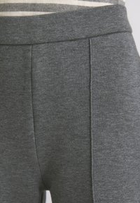 Zbliżenie na szare spodnie materiałowe z wysokim stanem i pionowymi detalami szwów.