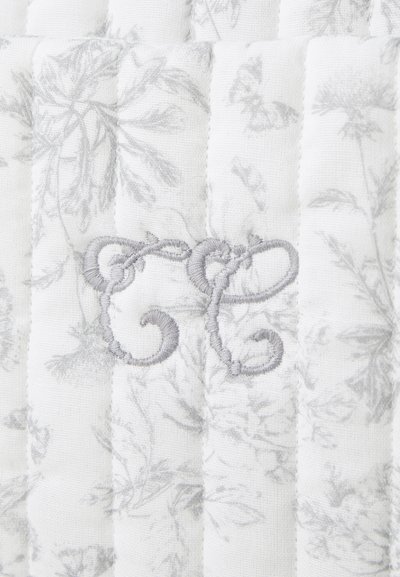 Tessuto imbottito bianco con motivo floreale grigio; presenta le iniziali grigie ricamate "GC" in un elegante corsivo. Texture morbida.