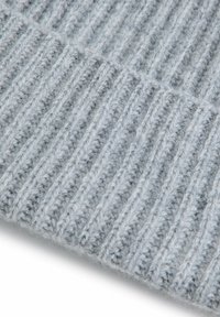 Szara dzianina z wełny o pionowej prążkowanej fakturze. Miękka, puszysta powierzchnia z naprzemiennymi wypukłymi i płaskimi pasami.