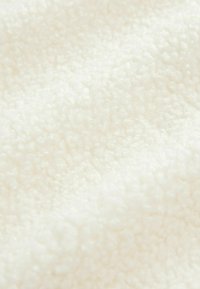 Gros plan d'un tissu doux, blanc et moelleux avec une surface texturée et pelucheuse ressemblant à du tissu polaire ou sherpa.