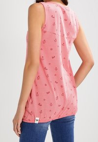 Tank top w paski w kolorze czerwonym i białym, z drobnymi wzorami kotwic i serc. Lekka tkanina z zaokrąglonym dołem i detalem metki z boku.