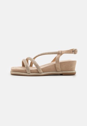 Sandales compensées beiges avec des brides entrecroisées, en suède texturé et avec un détail métallique. Design à bout ouvert et bride de cheville avec boucle.