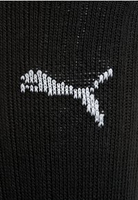 Tela de punto negra con un logotipo de Puma blanco cosido en el centro.