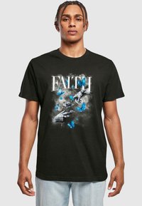 Sort bomulds T-shirt med et grafisk design af blå sommerfugle og hænder, med ordet "FAITH" i fed hvid skrift.