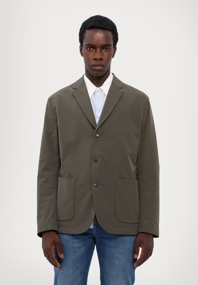 Olive green blazer with notched lapels, two front pockets, and black buttons, layered over a blue and white striped shirt.