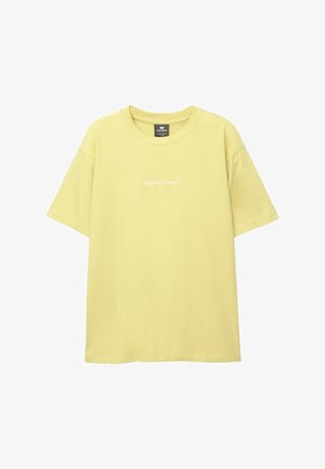 Geel katoenen T-shirt met korte mouwen, ronde hals en subtiele witte logo-afwerking aan de voorkant. Soepele textuur en ontspannen pasvorm.