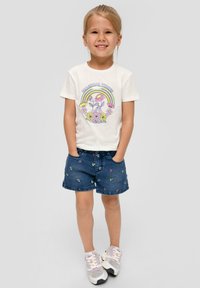 Weißes Baumwoll-T-Shirt mit "MAGICAL TIMES" Grafik und Regenbogen-Design; blaue Denim-Shorts mit mehrfarbiger Blumenstickerei; graue Sneakers.