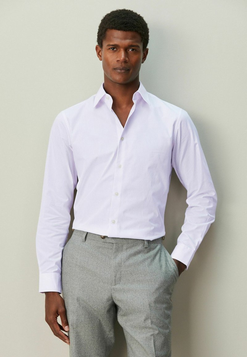 Hellviolettes gestreiftes Hemd mit Knöpfen und Kragen, kombiniert mit grauer, strukturierter Hose. Lange Ärmel und Standardmanschetten, mit lockerem Sitz.